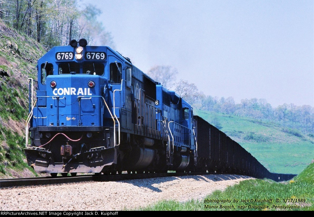 Conrail SD50 6769, leads a load of coal from Bailey mine and tops the grade at mp 11 on the MGA, Monongahela Railways Manor Branch, near Sycamore, Pennsylvania. May 17, 1989. 